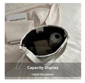Detail view of small bucket bag showing capacity for phone, umbrella and wallet