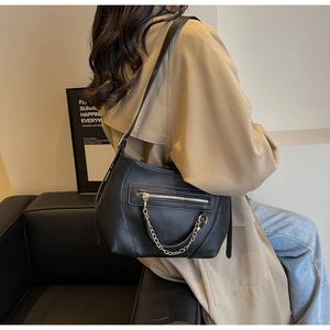 Black pebbled leather crescent shoulder bag styled on a khaki coat with gold chain detail