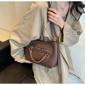 Detailed macro view of dark brown pebbled leather texture and gold chain on shoulder bag
