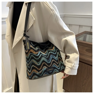 Detailed close-up of woven shoulder bag with wavy pattern texture on model's white coat