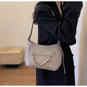 Detail view of beige lychee leather shoulder bag with decorative zipper and metal chain