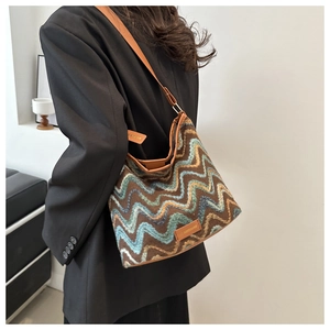 Detailed close-up of wool shoulder bag featuring colorful wavy stripes and a leather logo tag