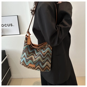 Detail of wavy knit bucket bag in brown and blue with premium leather shoulder strap