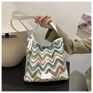 Close-up of knit wave texture and white leather strap on a stylish shoulder bucket bag