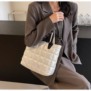Vue détaillée d'un sac cabas matelassé blanc avec poignées en cuir noir et bandoulière
