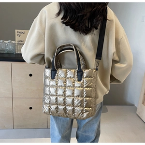 Sac fourre-tout matelassé champagne avec bandoulières noires porté par un mannequin
