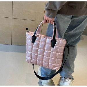 Détail d'un sac cabas matelassé rose avec poignées noires et bandoulière amovible