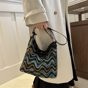 Ethnic chevron knit bucket bag with leather handles shown on a beige winter coat