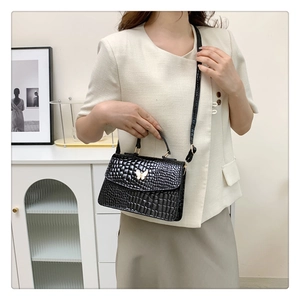 Detail of black crocodile texture mini bag with gold butterfly clasp on a side view