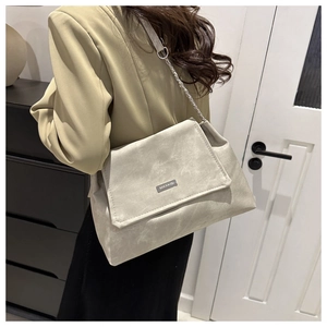 Modern light gray faux leather crossbody bag with chain strap shown on model's shoulder