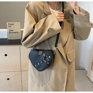 Détail des rivets argentés et de la boucle décorative sur le sac à bandoulière cœur noir