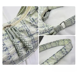 Detail view of woven houndstooth bag showing dual zippers and adjustable metal buckle strap
