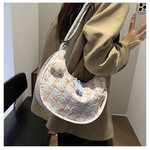 Detail of retro houndstooth half-moon crossbody bag with cute plush toast charm accessory