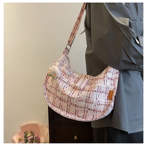 Detailed view of pink houndstooth crescent bag with cute peach plush charm