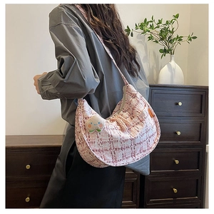 Detail of pink and white tweed hobo bag with a cute plush peach pendant on the side