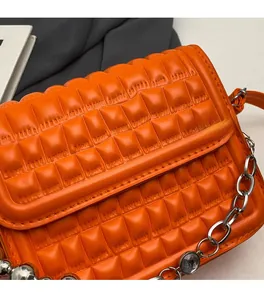 Gros plan d'un sac matelassé orange en similicuir avec chaîne argentée et strass