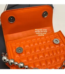 Détail du sac matelassé orange vif montrant deux boutons magnétiques argentés et des perles