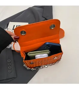 Détail intérieur d'un sac matelassé orange montrant l'espace pour téléphone et objets