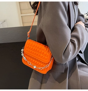 Détail du sac orange matelassé géométrique avec chaîne en argent porté à l'épaule