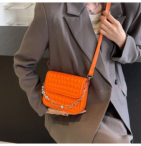 Détail du sac à rabat matelassé orange avec chaîne à perles argentées et bandoulière cuir