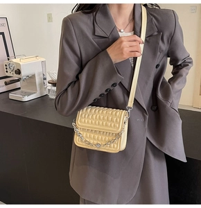 Petit sac bandoulière matelassé jaune pâle porté sur un blazer gris classique et chic