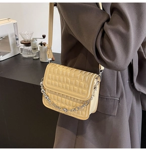 Détail d'un sac bandoulière jaune matelassé avec chaîne argentée sur un mannequin