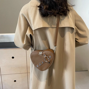 Sac à bandoulière marron en forme de cœur avec détails argentés porté par un mannequin