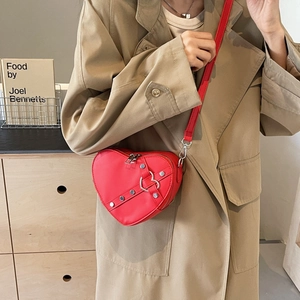 Sac à bandoulière rouge en forme de cœur avec clous argentés porté par un mannequin