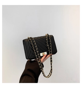 Detail of black quilted crossbody bag with gold lock and chain leather shoulder strap