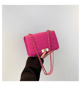 Detail of fuchsia chevron quilted bag with golden chain strap and swivel lock