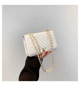 Close-up of white quilted crossbody bag featuring gold metal chain and twist-lock closure