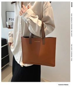 Detail of classic brown leather tote bag with gold logo text and fine grain texture