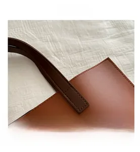 Close-up of brown leather briefcase handle with golden Fashion Bags text and stitching