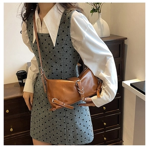 Brown leather crossbody bag with silver buckle detailing shown in an elegant interior