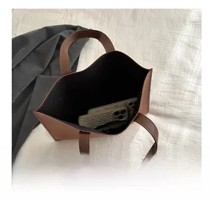 Top view of spacious interior in brown leather tote bag showing phone and cables
