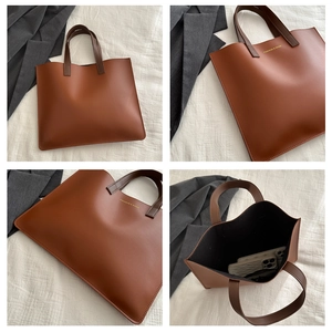 Detail view of large brown leather tote bag with internal capacity and golden logo