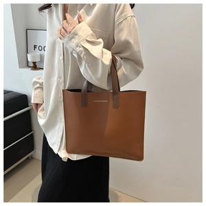 Detail of tan leather tote bag with contrasting dark brown handle and fashion lettering
