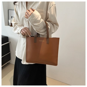 Detail of vintage brown leather tote bag showing smooth matte texture and gold embossed text