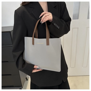 Detail of grey tote bag with brown handles and golden fashion logo for work