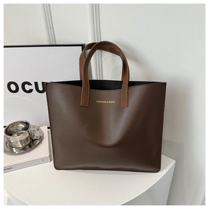 Close-up of deep brown leather tote bag with gold lettering and minimalist design