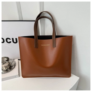 Close-up of caramel leather tote bag with gold logo and stylish brown handles