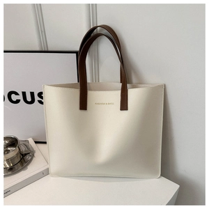 Detail of minimalist cream tote bag with brown handles and gold fashion lettering