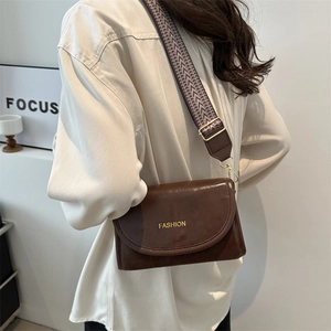 Brown retro crossbody bag with golden Fashion text and wide geometric weave strap