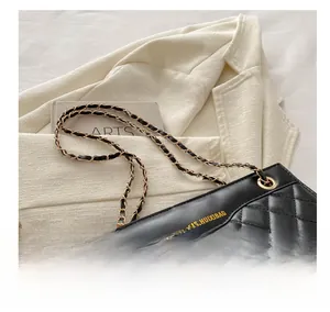 Close-up of quilted leather texture and gold-tone chain strap on black shoulder bag