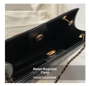 Detail of gold magnetic closure on black quilted leather bag with woven chain strap