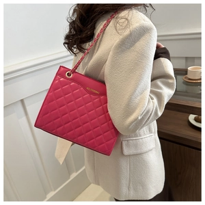 Close-up of pink quilted crossbody bag with gold chain strap worn by a model