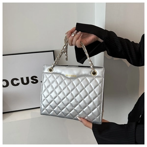 Detail view of silver quilted handbag with gold chain strap and metallic finish