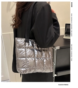 Close-up of quilted silver metallic tote bag with black strap on a shoulder