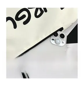 Detail of front zipper pocket on beige crossbody bag holding a large smartphone
