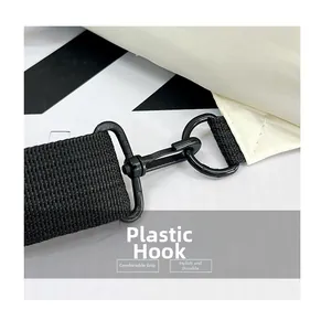 Detail of durable black plastic hook and thick nylon strap on off-white crossbody bag